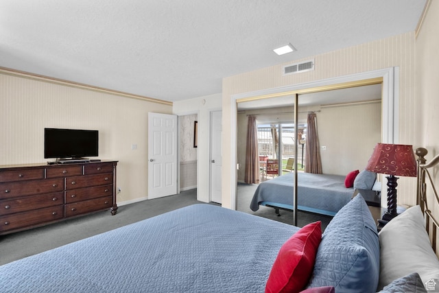 carpeted bedroom featuring a textured ceiling, visible vents, baseboards, and a closet