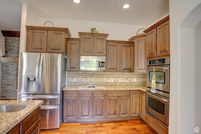 kitchen featuring light stone countertops, backsplash, and appliances with stainless steel finishes