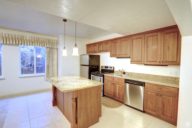 kitchen with a center island, decorative light fixtures, a sink, appliances with stainless steel finishes, and light stone counters