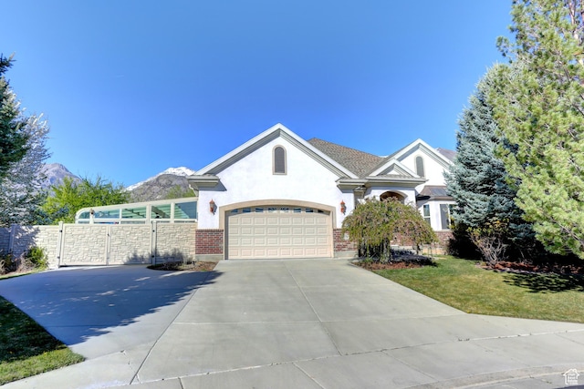 view of front of home with a front yard, concrete driveway, fence, stucco siding, and a gate