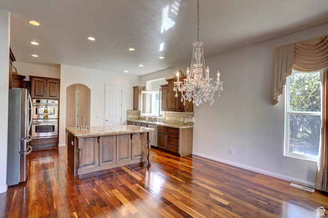 kitchen featuring stainless steel appliances, arched walkways, a sink, and recessed lighting