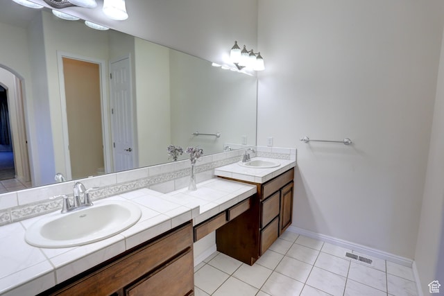 bathroom featuring tile patterned flooring, double vanity, visible vents, and a sink