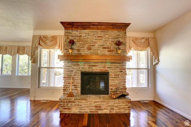 unfurnished living room with a wealth of natural light, wood finished floors, and baseboards