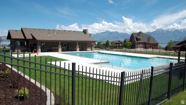 community pool featuring a patio, fence, a lawn, and a mountain view