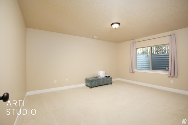 spare room featuring a textured ceiling, visible vents, baseboards, and carpet