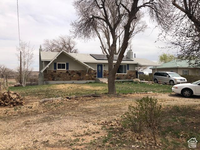 view of front of property with stone siding and roof mounted solar panels
