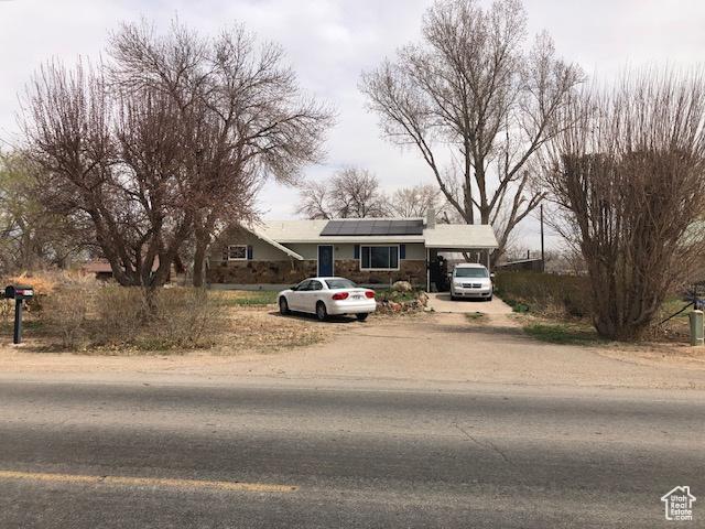 bungalow with an attached carport, solar panels, and driveway