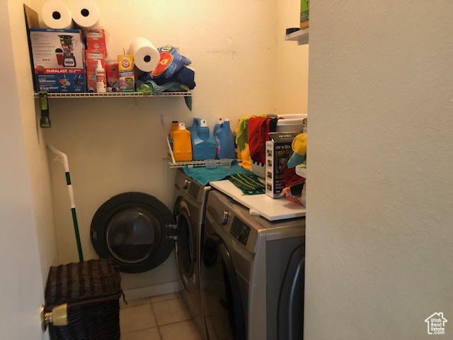 clothes washing area featuring tile patterned flooring, washer and clothes dryer, and laundry area