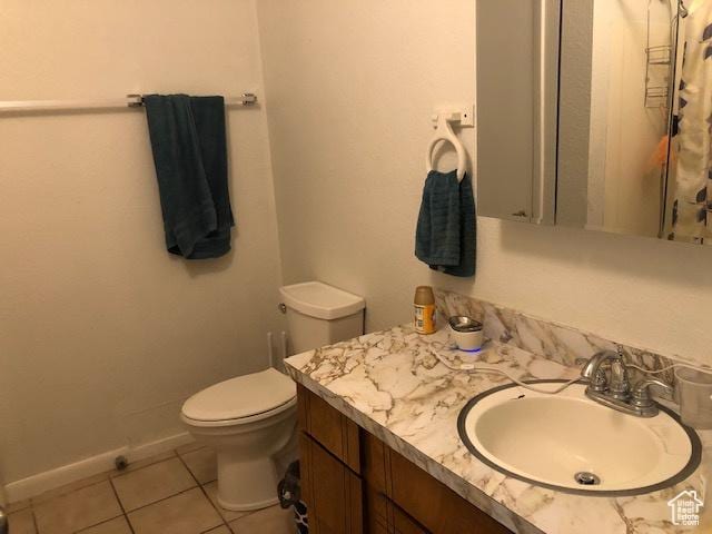 bathroom featuring toilet, tile patterned flooring, baseboards, and vanity
