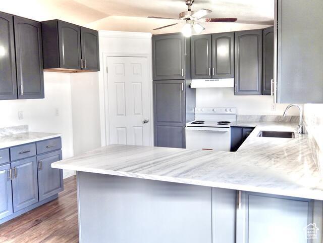 kitchen featuring a sink, ceiling fan, a peninsula, under cabinet range hood, and white electric range