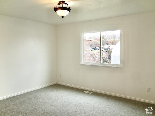 carpeted spare room with visible vents and baseboards