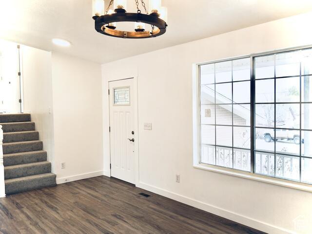 entryway featuring dark wood-type flooring, an inviting chandelier, and baseboards