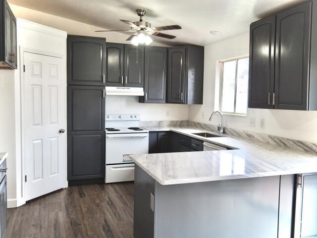 kitchen featuring a peninsula, under cabinet range hood, white electric range oven, ceiling fan, and a sink