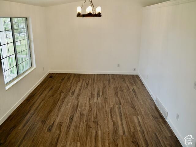 unfurnished dining area with visible vents, a notable chandelier, dark wood-style floors, and baseboards