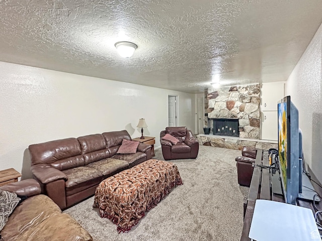 carpeted living area with a stone fireplace and a textured ceiling