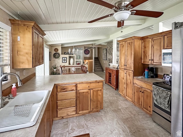 kitchen featuring stainless steel appliances, a sink, beamed ceiling, a peninsula, and ceiling fan