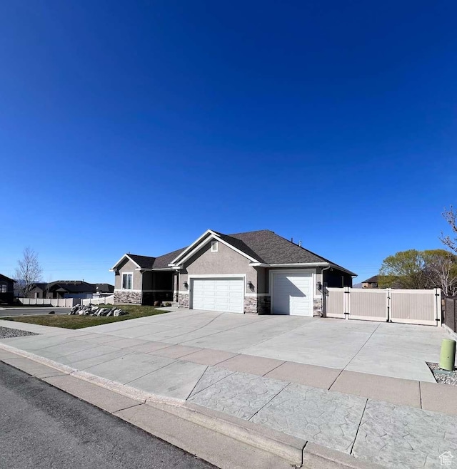ranch-style house featuring a gate, driveway, stone siding, a garage, and stucco siding