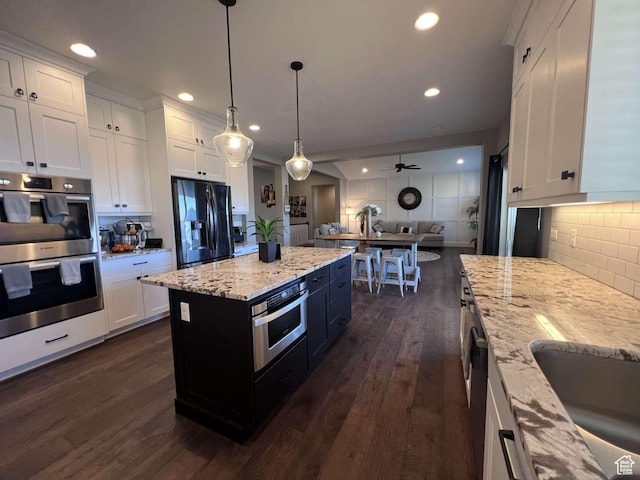 kitchen with white cabinets, stainless steel appliances, tasteful backsplash, open floor plan, and dark wood-style flooring