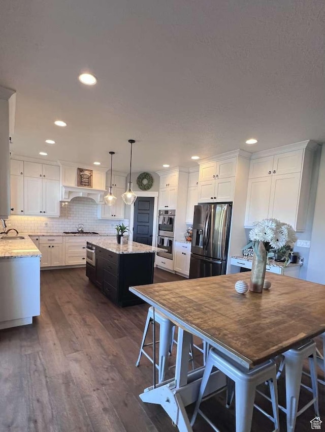 kitchen with stainless steel appliances, white cabinetry, a sink, light stone countertops, and dark wood-style flooring