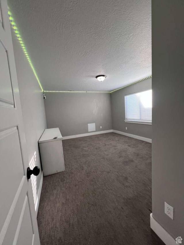 carpeted spare room with baseboards and a textured ceiling