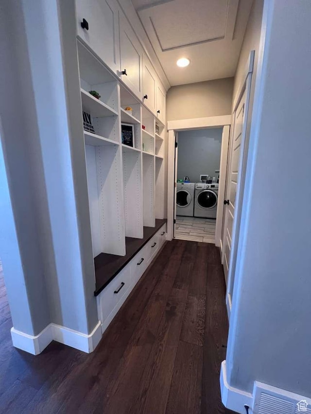 mudroom featuring dark wood finished floors, visible vents, baseboards, and separate washer and dryer