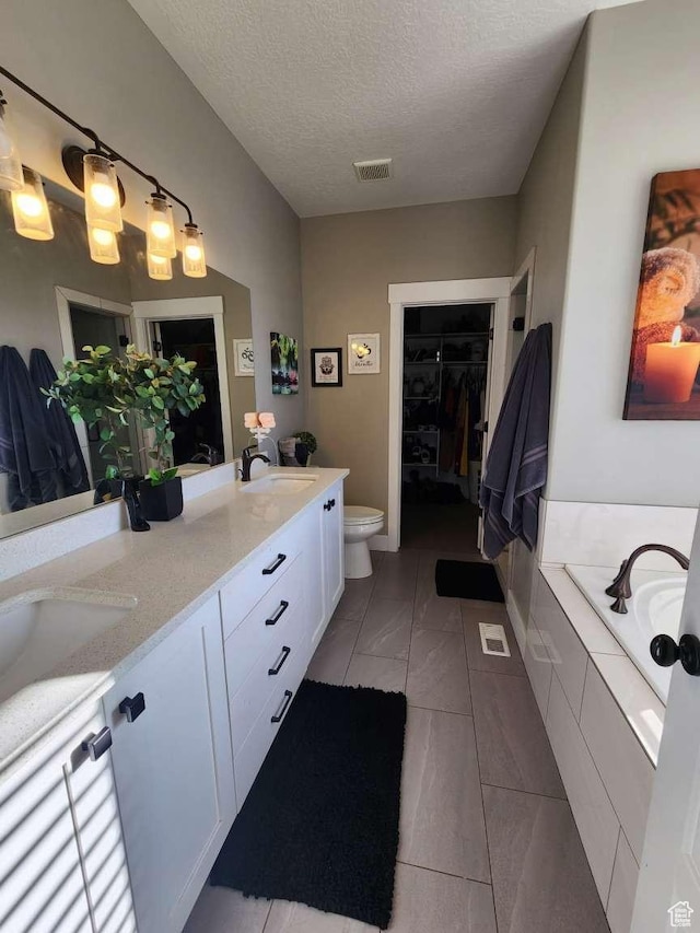 bathroom with a sink, a textured ceiling, double vanity, toilet, and visible vents