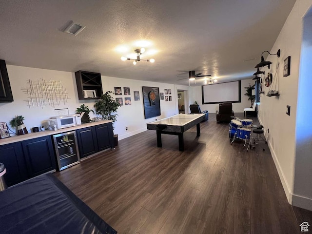 playroom featuring dark wood finished floors, visible vents, baseboards, and ceiling fan with notable chandelier
