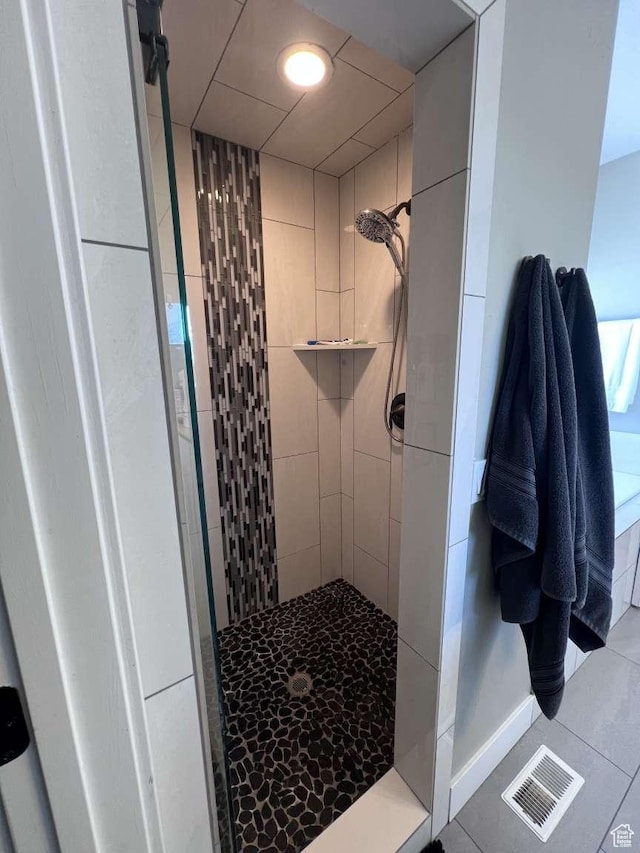 full bathroom with tile patterned floors, baseboards, visible vents, and tiled shower