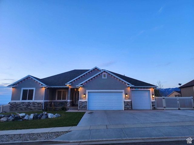 craftsman house with a front lawn, a gate, driveway, stone siding, and an attached garage