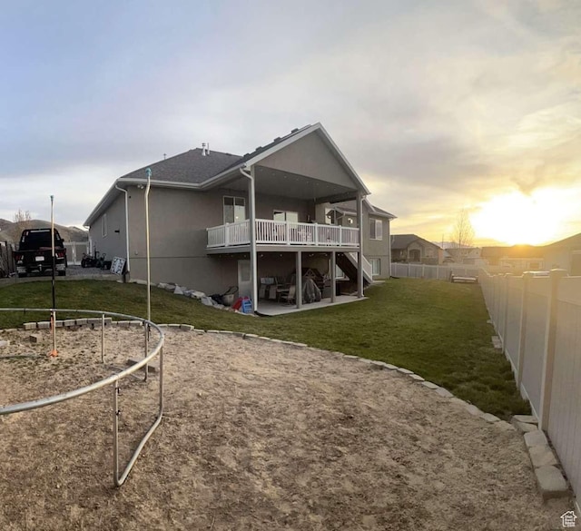 back of house with a fenced backyard, a lawn, a deck, a patio, and stucco siding