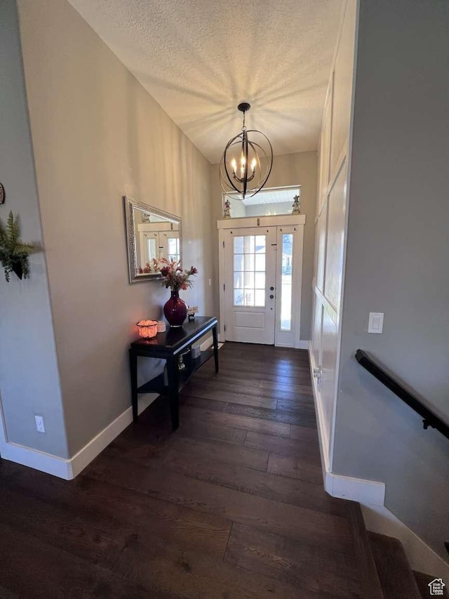 entryway featuring baseboards, dark wood-style floors, a textured ceiling, and a chandelier