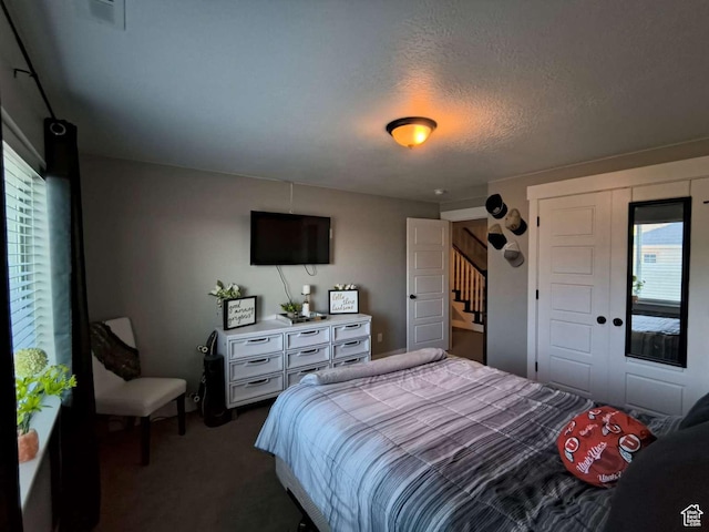 bedroom featuring visible vents, dark carpet, and a textured ceiling