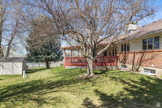 view of yard featuring an outbuilding, fence, a wooden deck, and a storage shed