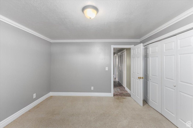 unfurnished bedroom with a closet, baseboards, a textured ceiling, crown molding, and light colored carpet