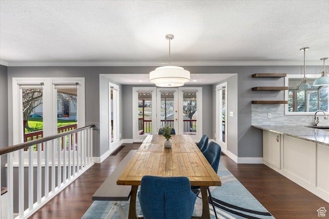 dining space featuring french doors, a textured ceiling, ornamental molding, and dark wood finished floors