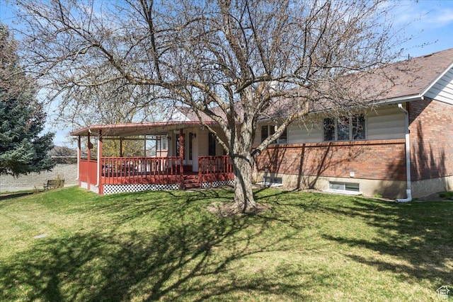 rear view of property with brick siding, a deck, and a lawn