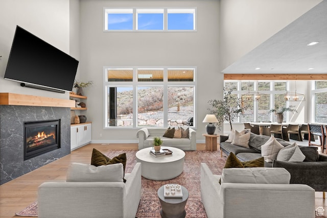 living room featuring a high ceiling, wood finished floors, a notable chandelier, and a fireplace