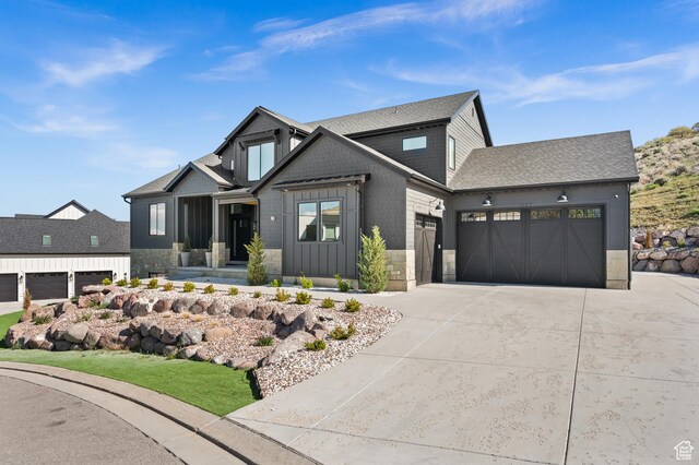 view of front of property featuring a garage, board and batten siding, driveway, and stone siding
