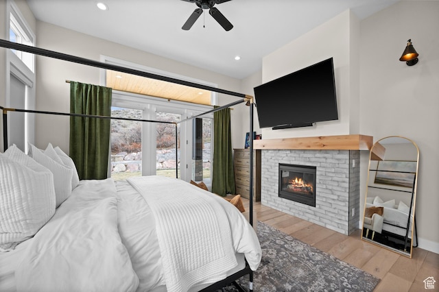 bedroom with recessed lighting, a glass covered fireplace, multiple windows, and wood finished floors
