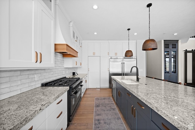 kitchen with white cabinets, premium appliances, glass insert cabinets, and a sink