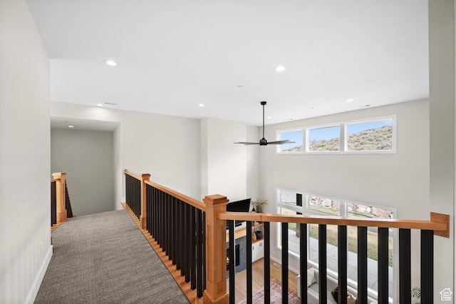 corridor featuring recessed lighting, baseboards, wood finished floors, and an upstairs landing