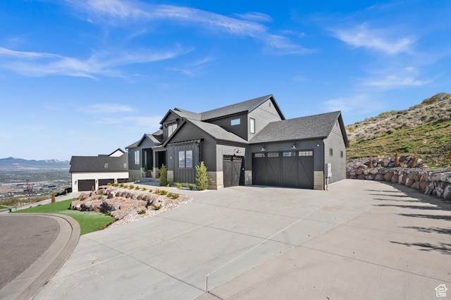 modern farmhouse with an attached garage, driveway, a mountain view, and roof with shingles