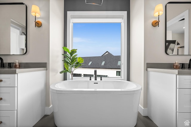 full bath with vanity, baseboards, and a soaking tub