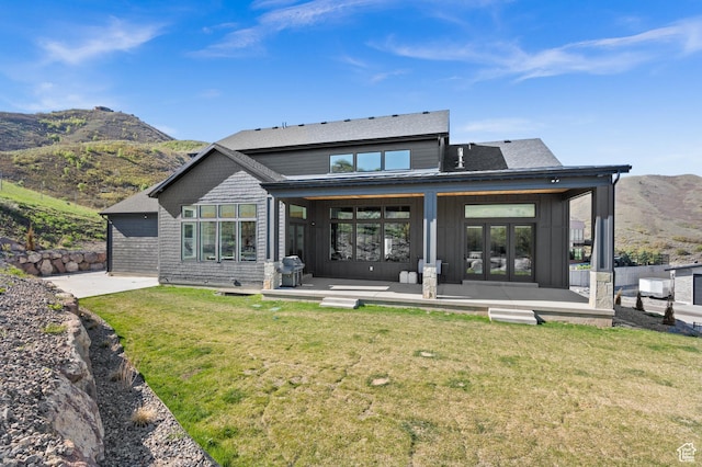 back of house with a patio, a mountain view, and a yard