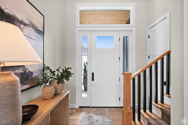 foyer entrance featuring baseboards, stairs, and wood finished floors