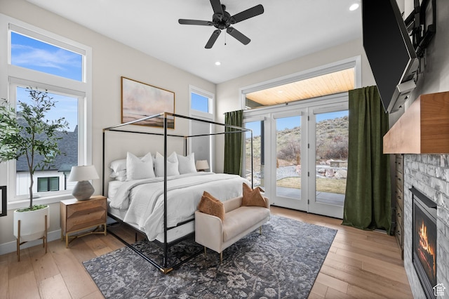 bedroom with a glass covered fireplace, access to outside, recessed lighting, a ceiling fan, and light wood finished floors