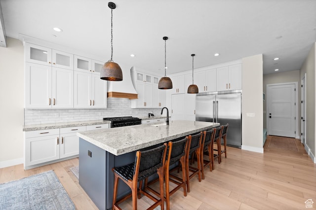 kitchen featuring baseboards, backsplash, custom exhaust hood, and built in fridge