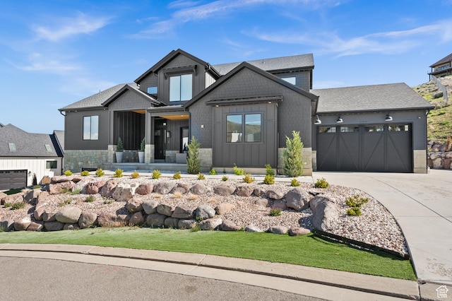 view of front of property featuring board and batten siding, an attached garage, driveway, and stone siding