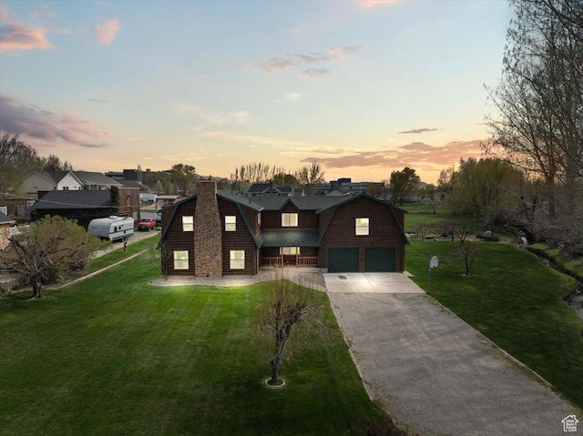 view of front of property with concrete driveway, a gambrel roof, a front lawn, and an attached garage