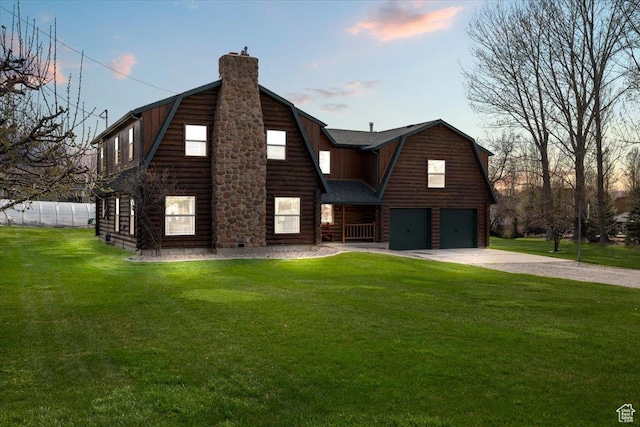 view of front of property with a chimney, driveway, a gambrel roof, a garage, and a front yard